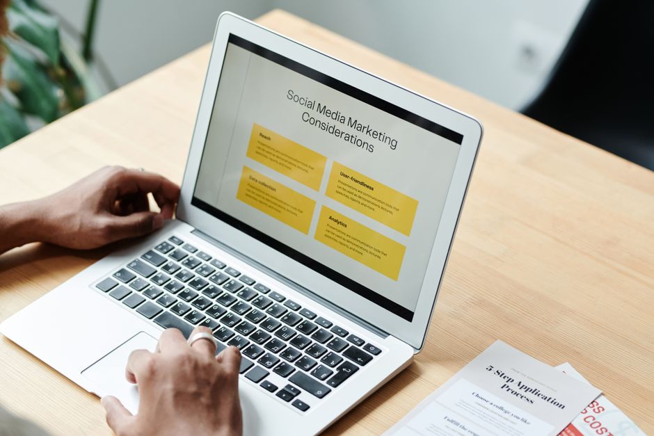 Marketing Turístico — A person using a laptop to review social media marketing strategies at home.