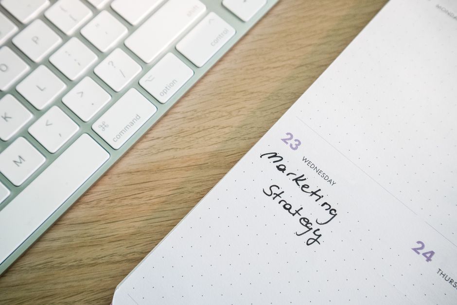 Marketing Turístico — Close-up of a desk with a keyboard and a calendar open to a marketing strategy note.